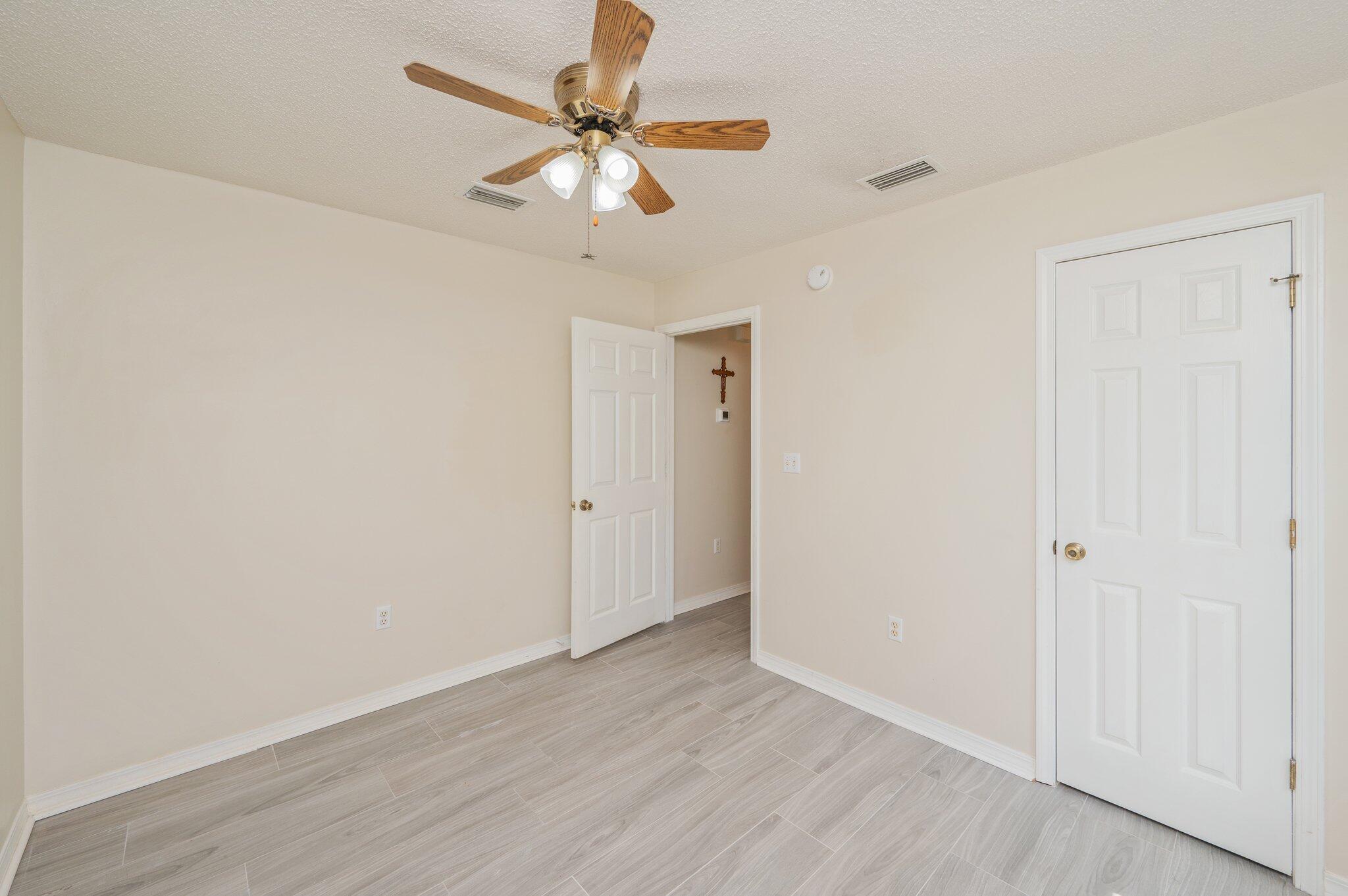642 Alysheba Drive Crestview, FL 32539 - Photo 21 of 32 an empty room with wooden floor and fan