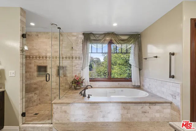 a bathroom with a tub a sink double vanity and a shower