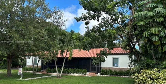 a front view of a house with a garden and tree