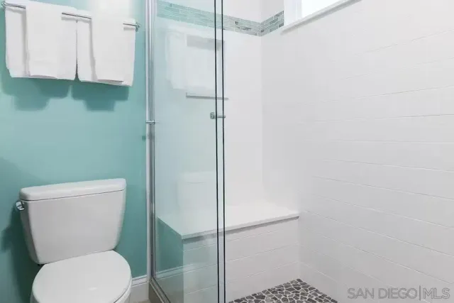 a white toilet sitting next to a shower