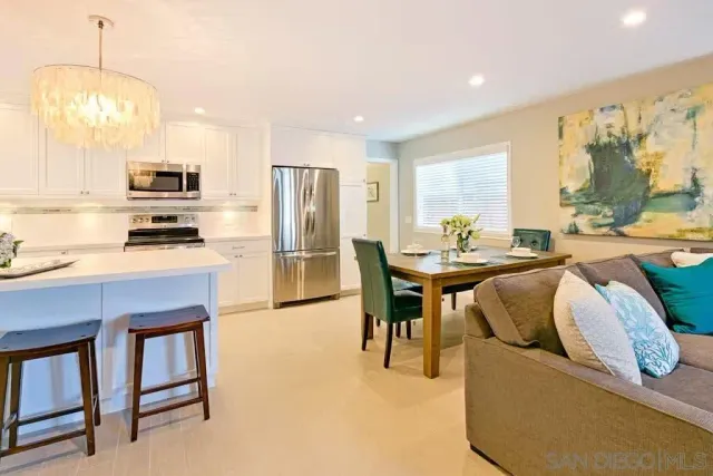 a kitchen with stainless steel appliances granite countertop a stove a refrigerator a sink a dining table and chairs with wooden floor