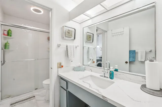 a bathroom with a granite countertop sink a toilet and shower