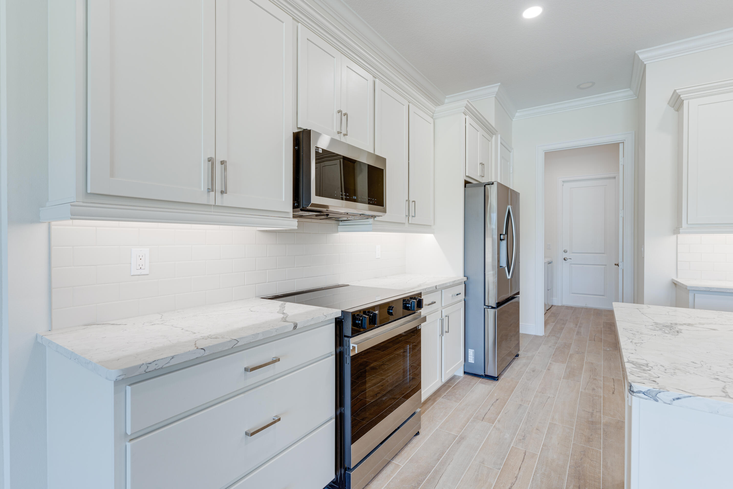 1805 Bridgepointe Circle, Unit 3 Vero Beach, FL 32967 - Photo 5 of 28 a kitchen with stainless steel appliances white cabinets and a stove a oven with wooden floor