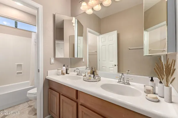 a bathroom with double vanity sinks a large mirror and a bathtub