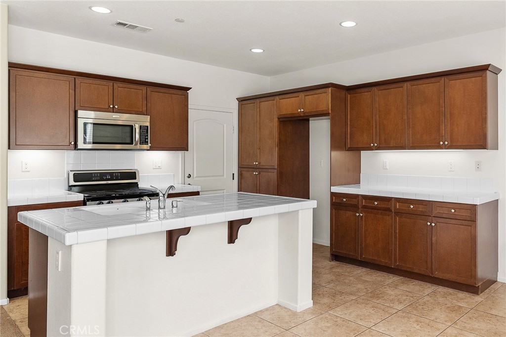 12047 Dewar Drive Riverside, CA 92505 - Photo 10 of 40 a kitchen with stainless steel appliances granite countertop a stove a sink and a microwave