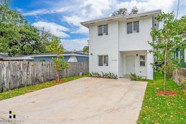 a front view of a house with a yard and potted plants
