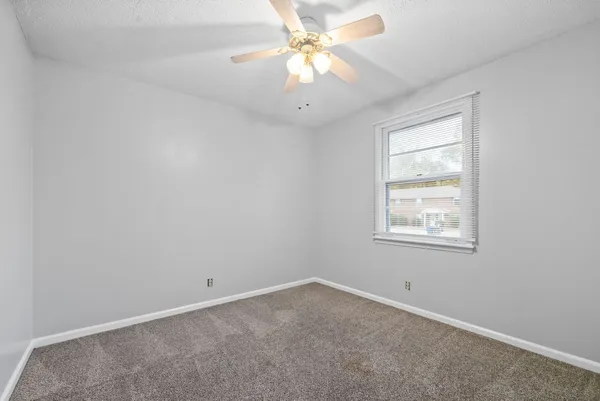 an empty room with a window and a chandelier fan