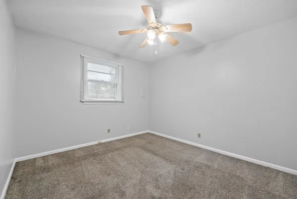 an empty room with a window and a fan