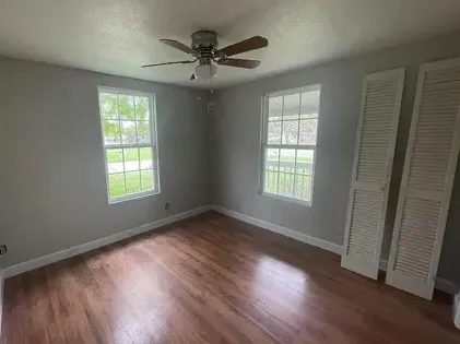 a view of an empty room with wooden floor and a window