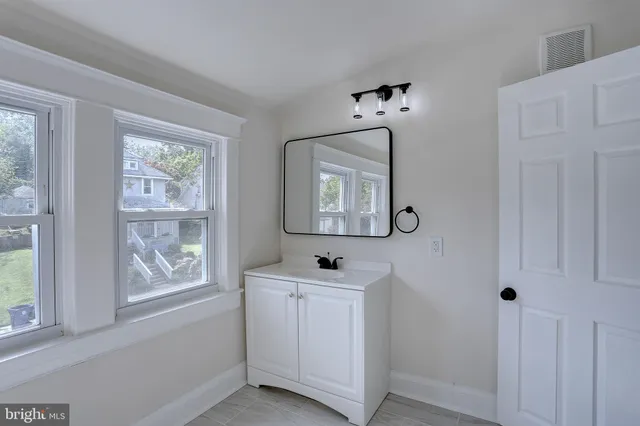 an empty room with wooden floor ceiling fan and windows