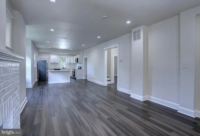 a living room with stainless steel appliances furniture a fireplace and wooden floor