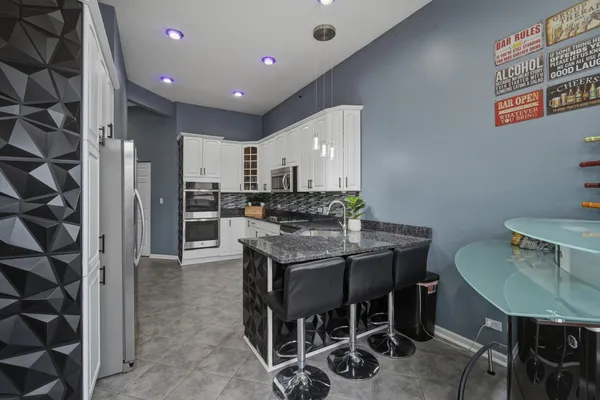 a kitchen with kitchen island a dining table chairs stainless steel appliances and cabinets