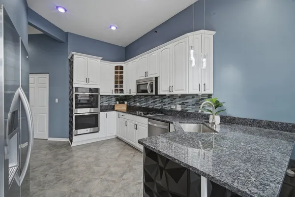 a kitchen with stainless steel appliances granite countertop a sink stove and refrigerator