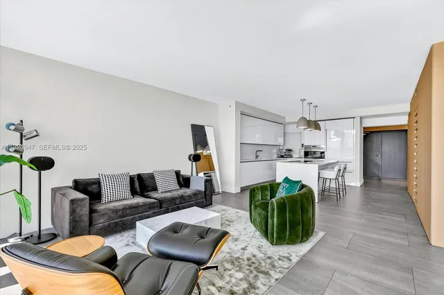 a living room with furniture a rug and kitchen view