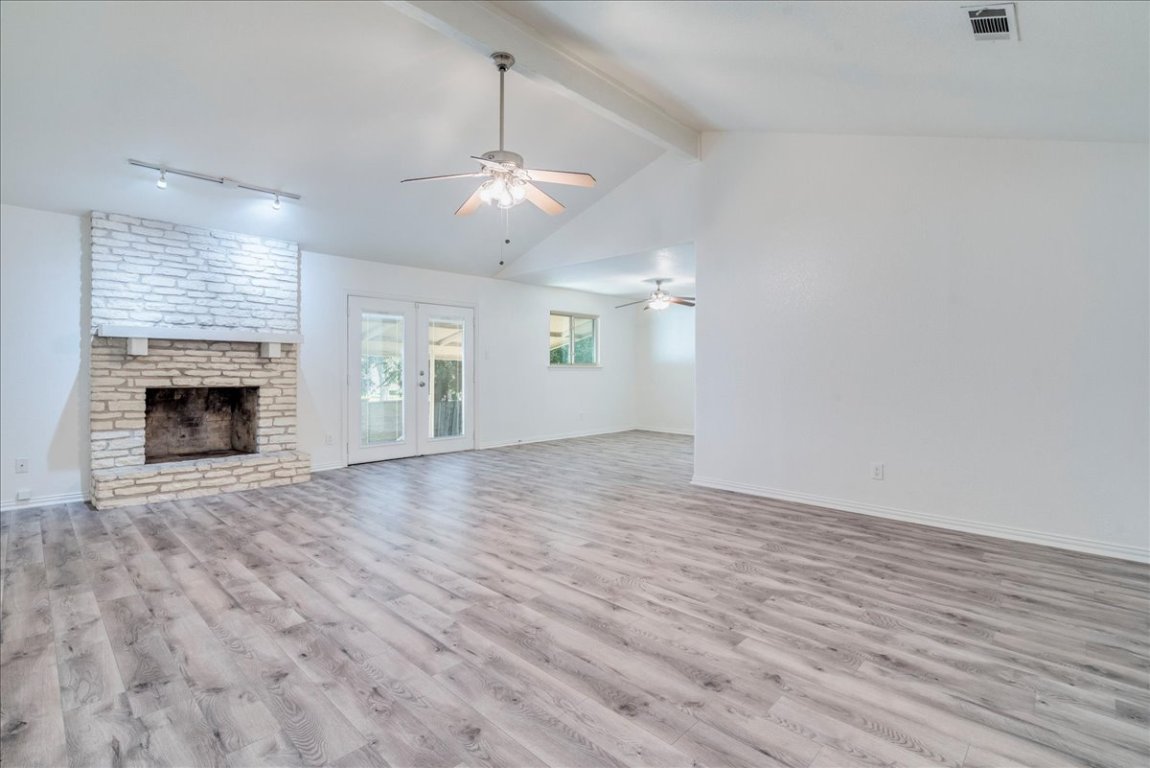 706 Windsor Road Round Rock, TX 78664 - Photo 7 of 29 an empty room with wooden floor fireplace and ceiling fan