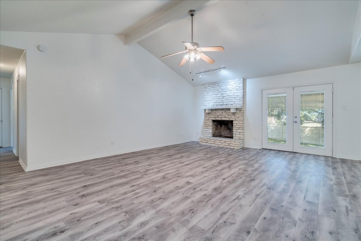 706 Windsor Road Round Rock, TX 78664 - Photo 10 of 29 an empty room with wooden floor fireplace and windows