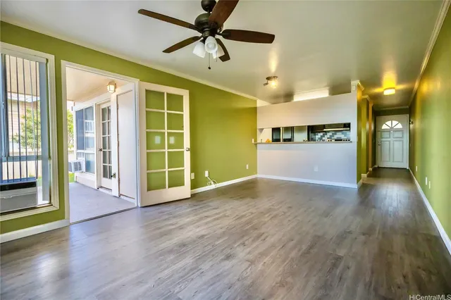 a view of a big room with wooden floor a ceiling fan and windows