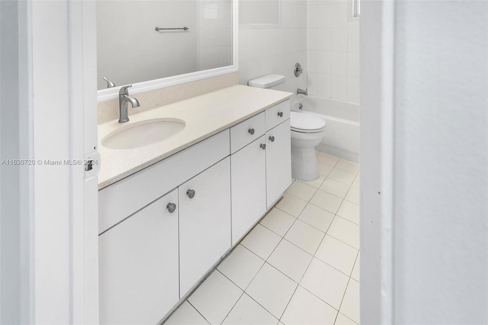 7430 Miami Lakes Drive, Unit E302 Miami Lakes, FL 33014 - Photo 12 of 29 a spacious bathroom with a granite countertop sink a toilet and a mirror