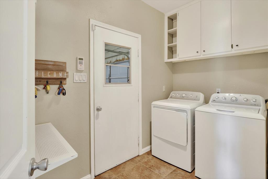 8877 Random Road Fort Worth, TX 76179 - Photo 26 of 40 Utility room featuring overhead white cabinetry with open shelving, a built-in folding shelf, and light-toned flooring