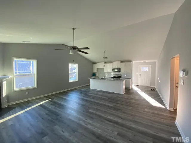 a view of an empty room with window and wooden floor