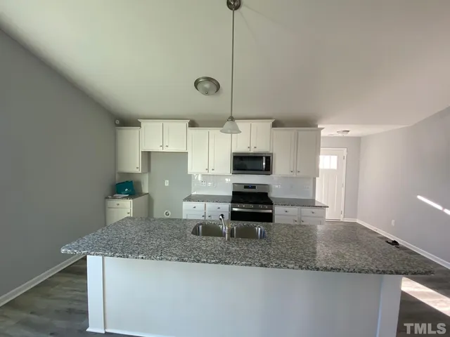 a kitchen with stainless steel appliances granite countertop a sink a microwave a stove and white cabinets