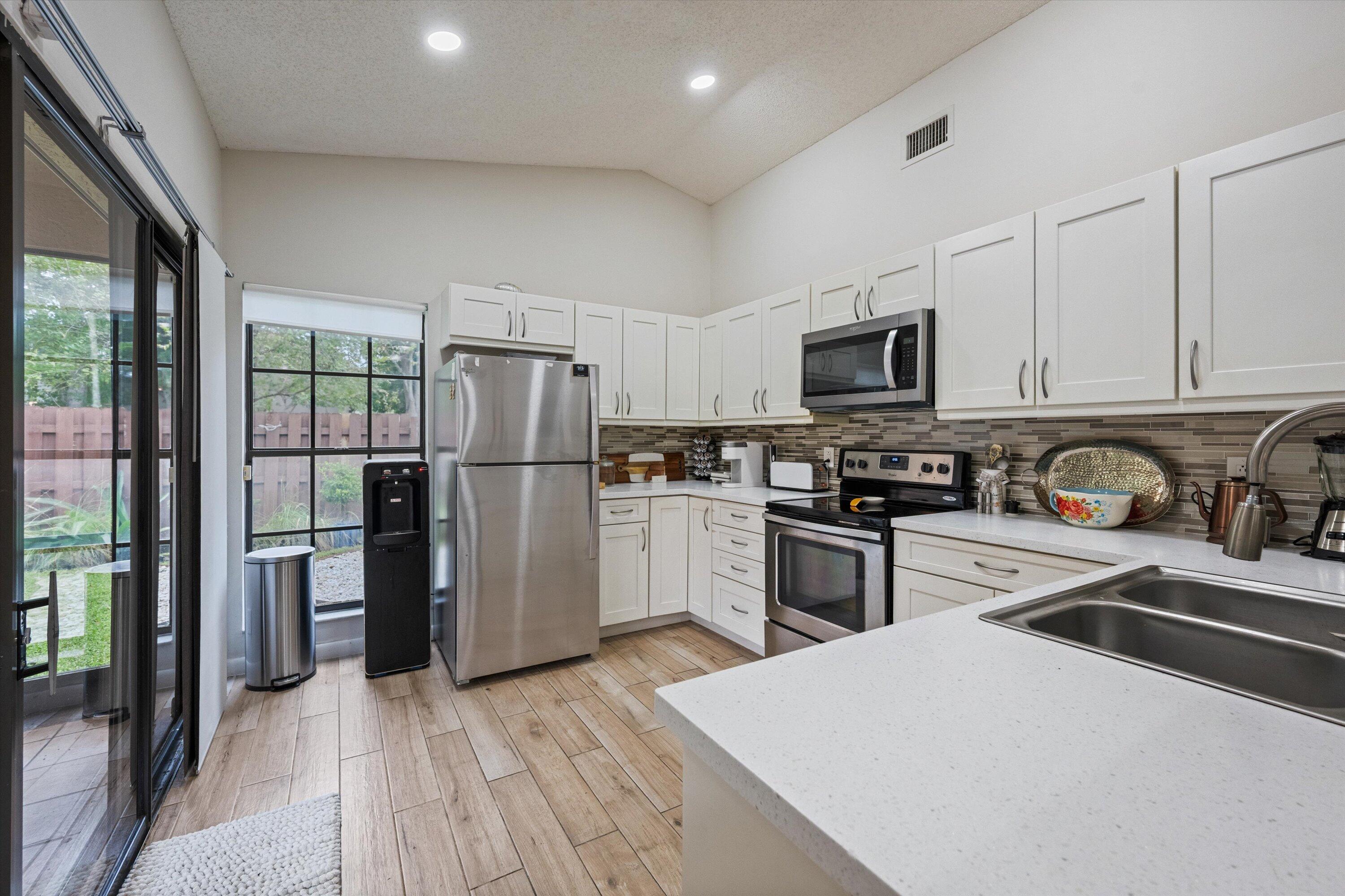 1769 Harborside Circle Wellington, FL 33414 - Photo 11 of 34 a kitchen with a refrigerator a stove top oven a sink and dishwasher with wooden floor