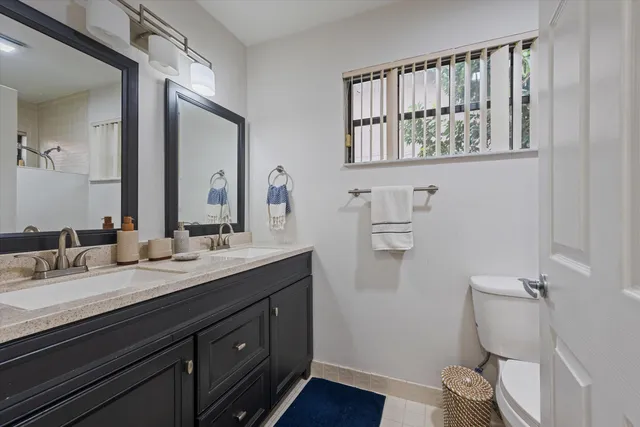 a bathroom with a granite countertop toilet sink and mirror