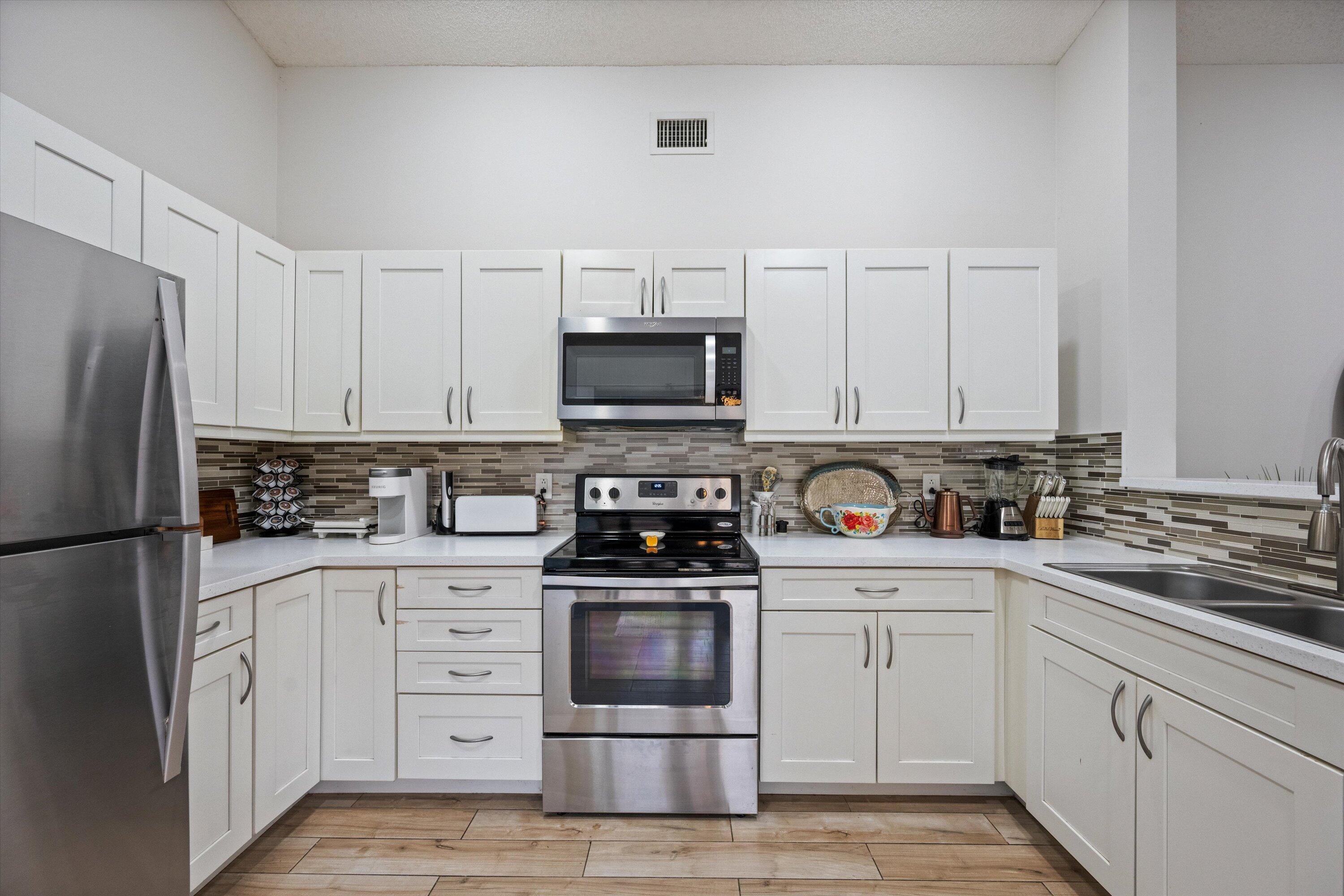 1769 Harborside Circle Wellington, FL 33414 - Photo 10 of 34 a kitchen with white cabinets and stainless steel appliances