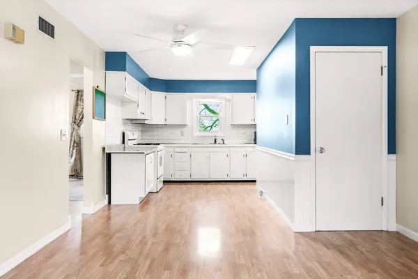 a view of a kitchen with kitchen island a sink wooden floor and a refrigerator