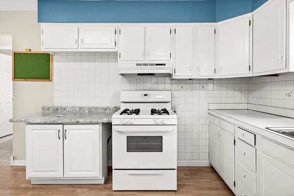 a kitchen with granite countertop white cabinets and white appliances