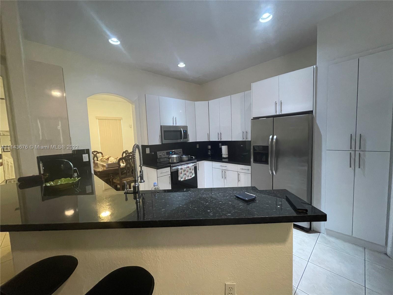 23744 Southwest 108th Court Homestead, FL 33032 - Photo 5 of 22 a kitchen with stainless steel appliances granite countertop a sink a stove top oven a counter space and cabinets
