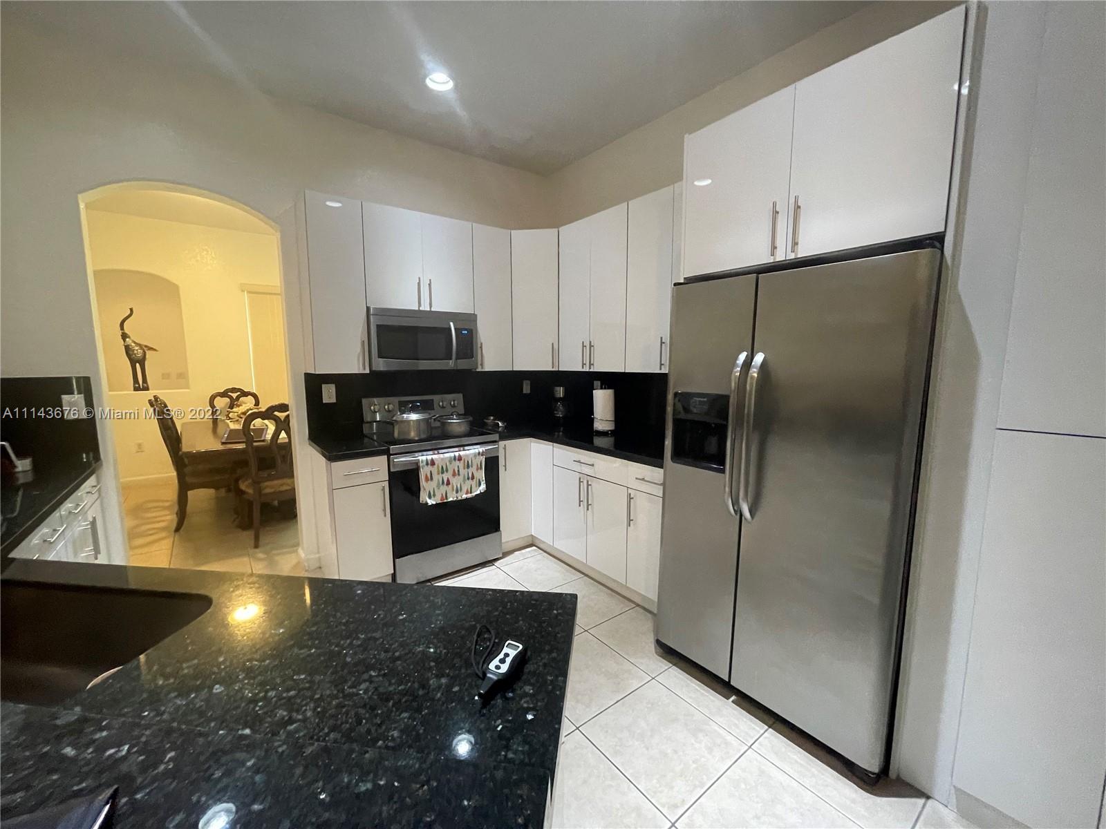 23744 Southwest 108th Court Homestead, FL 33032 - Photo 6 of 22 a kitchen with stainless steel appliances granite countertop a refrigerator a stove a microwave oven with white cabinets and wooden floor