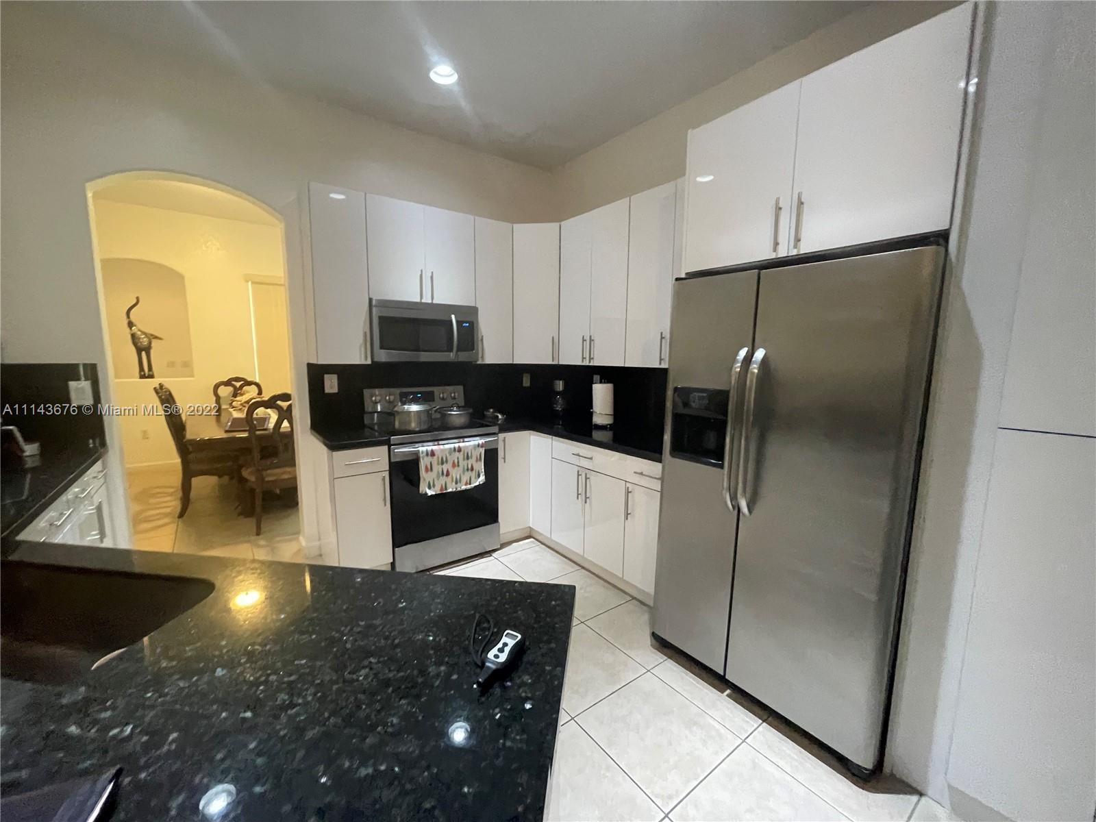 23744 Southwest 108th Court Homestead, FL 33032 - Photo 7 of 22 a kitchen with stainless steel appliances granite countertop a refrigerator a stove a microwave oven a sink with granite countertops and cabinets