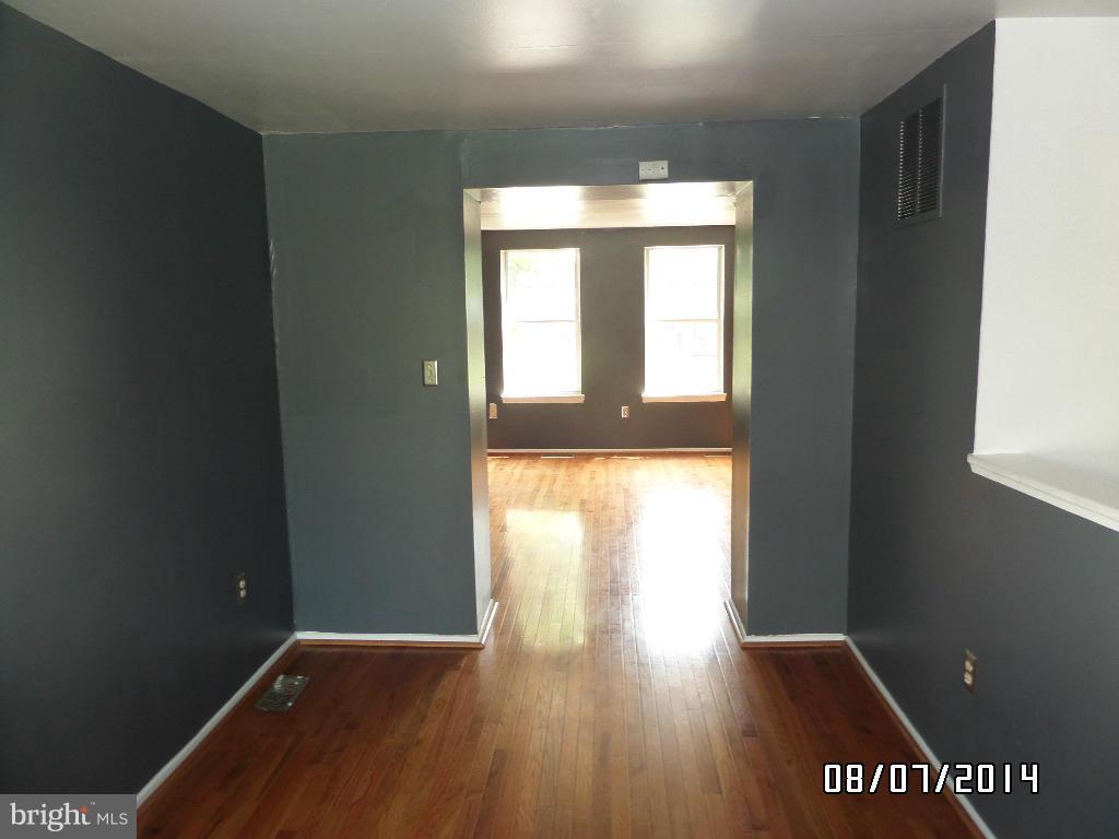 1363 Spelman Road Baltimore, MD 21225 - Photo 4 of 16 a view of an empty room with wooden floor and a window