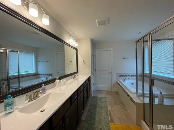 a spacious bathroom with a sink double vanity granite tub and shower