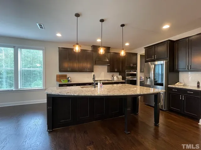 a kitchen with stainless steel appliances granite countertop a sink a stove a refrigerator and wooden floor
