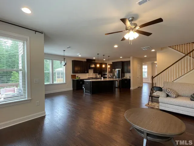 a living room with couches and kitchen view with wooden floor