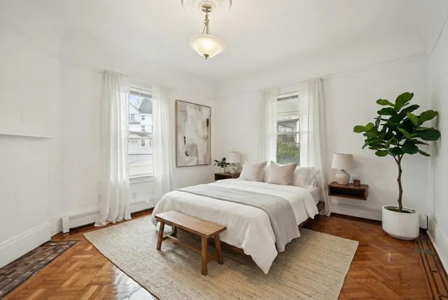 a bedroom with a bed table flowerpot and window
