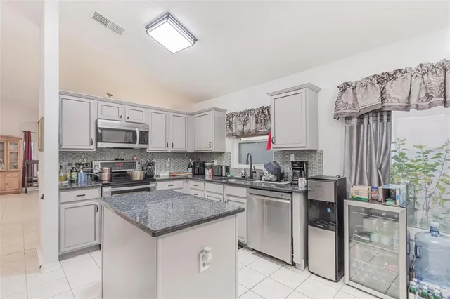 a kitchen with stainless steel appliances granite countertop a sink stove cabinets and refrigerator