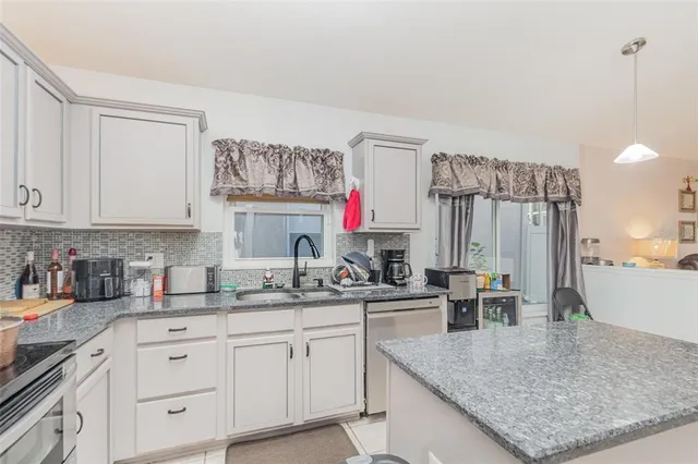 a kitchen with stainless steel appliances granite countertop a sink dishwasher and cabinets with wooden floor