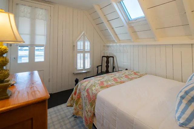 a bedroom with a bed a mirror on dresser and a chandelier