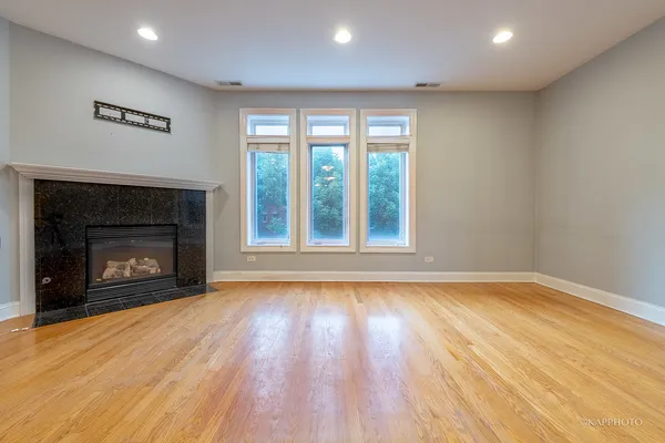a view of an empty room with wooden floor fireplace and a window