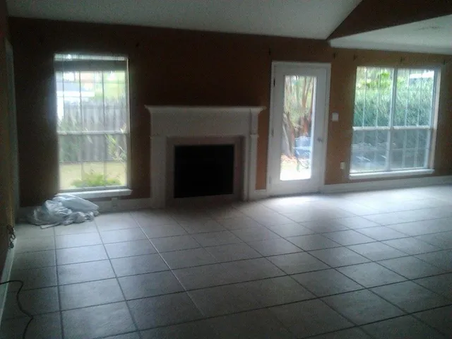 a view of an empty room with a fireplace and a window