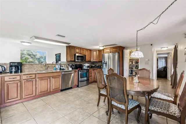 a kitchen with stainless steel appliances kitchen island granite countertop a table chairs and a sink
