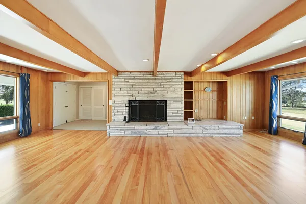 a view of empty room with wooden floor and fireplace