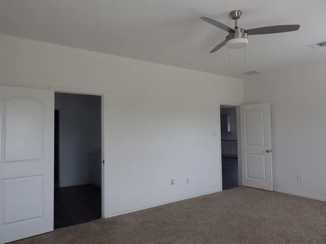 an empty room with a ceiling fan and a window