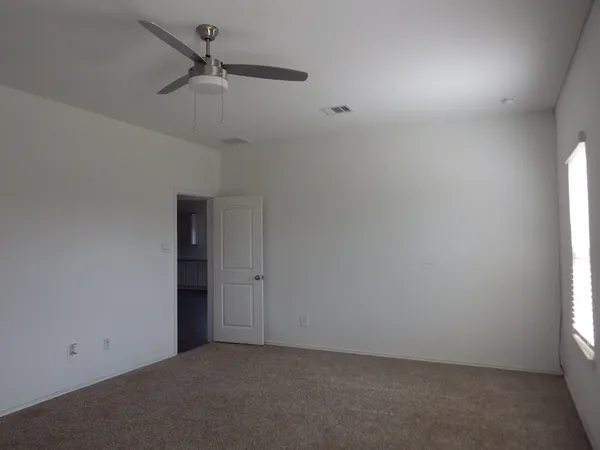 an empty room with a window and a fan