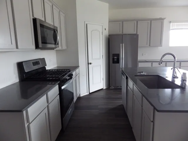 a kitchen with stainless steel appliances granite countertop a sink stove and refrigerator