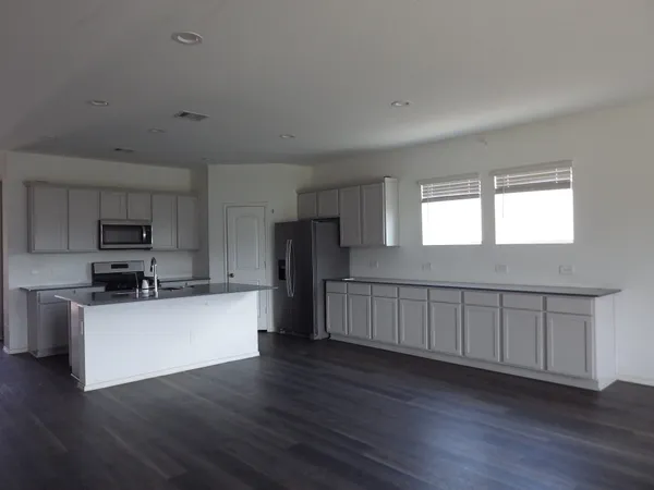a kitchen with stainless steel appliances wooden floors and white walls