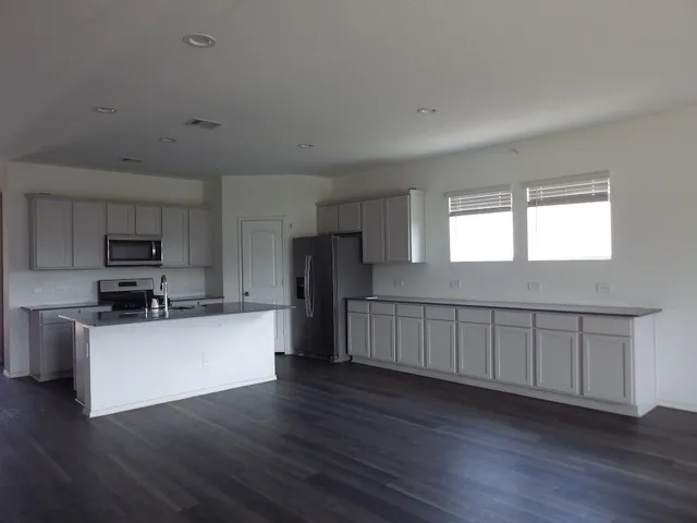 a kitchen with stainless steel appliances wooden floors and white walls